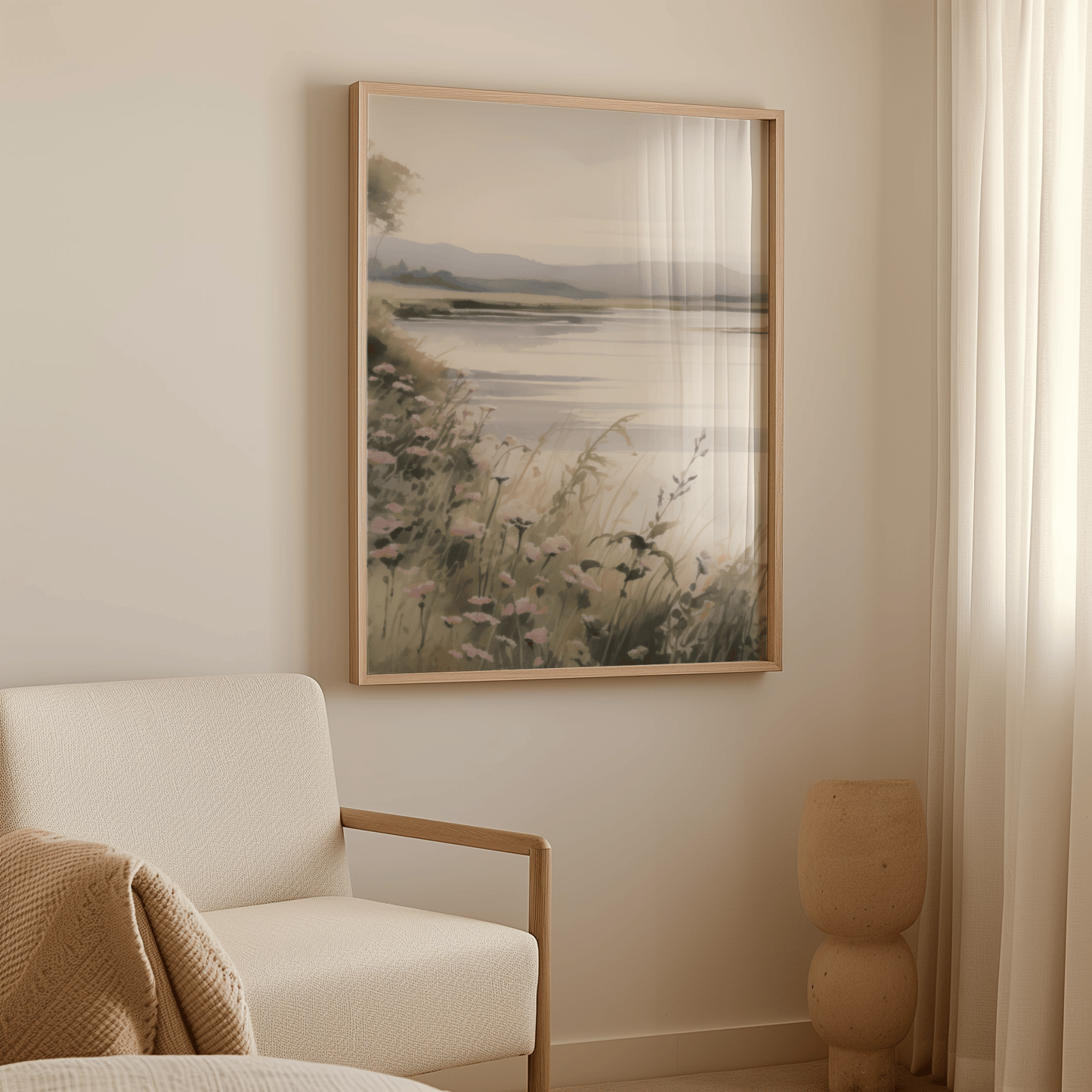 Large framed neutral landscape wall art with flowers in cozy modern living room next to beige armchair