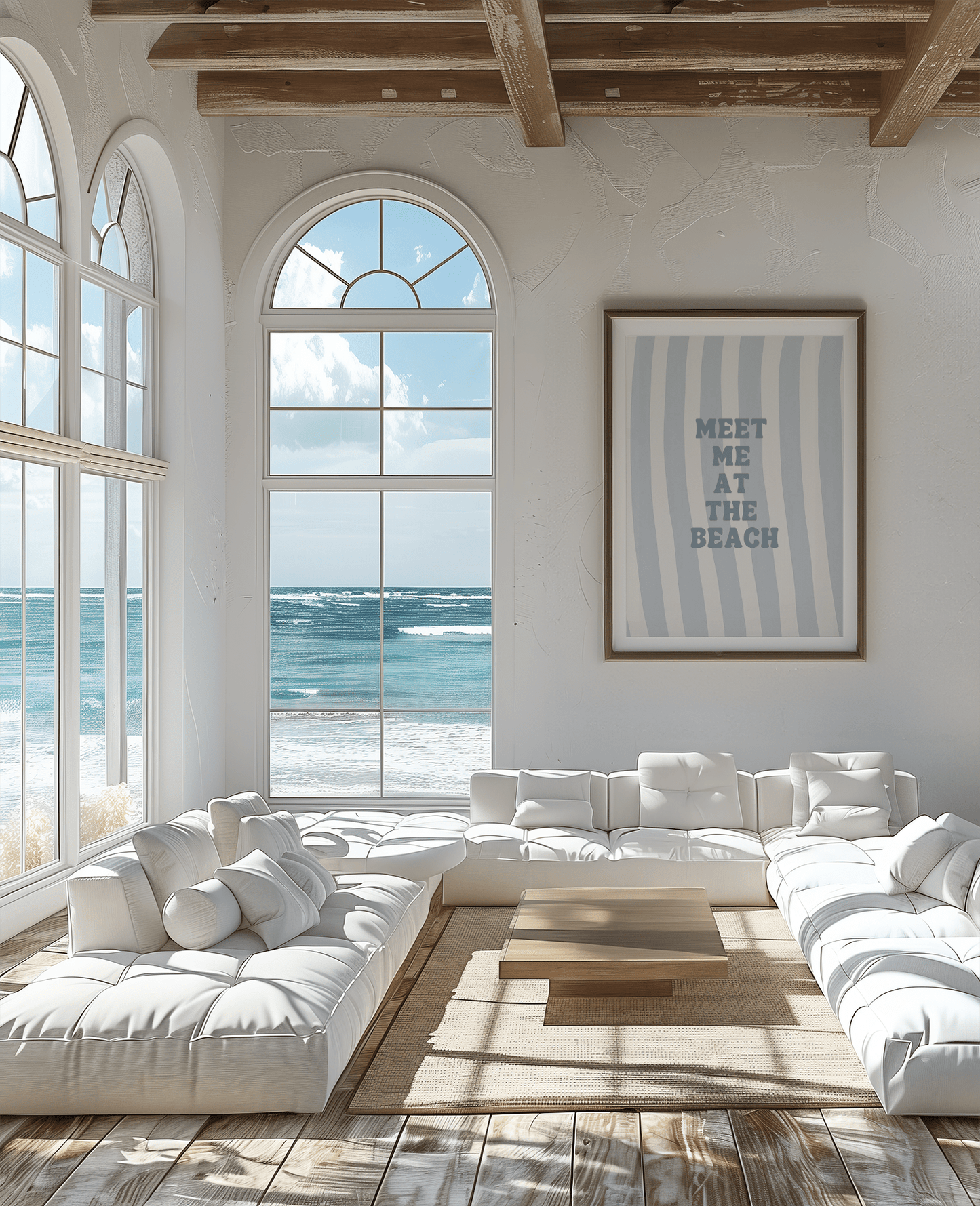 Gold framed meet me at the beach wall art above a white sofa in a coastal living room with ocean view