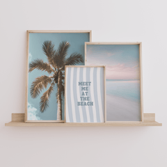Meet me at the beach wall art in natural frame styled on a shelf with palm tree and beach prints set of 3