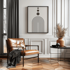 Mid-century arch print in a black frame above a leather chair in a bright reading nook