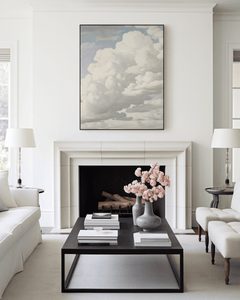 Modern living room with vintage neutral clouds wall art print above fireplace, coffee table, and decorative elements.