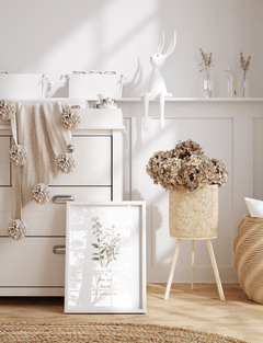 Minimal nursery wall art with a delicate floral illustration in a white frame, styled with light wood furniture