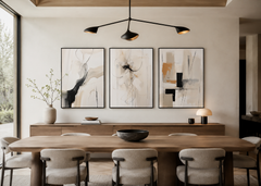 Three-piece abstract wall art gallery displayed in a contemporary dining room featuring warm wood furniture, black frames, neutral tones, and modern designer styling.
