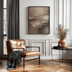 Modern living room with brown leather chair, moody brown abstract framed print, and decorative elements.