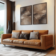 Set of 2 brown and beige moody abstract wall art prints in dark frames above a tan leather sofa in a modern living room