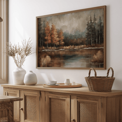 Moody fall landscape wall art in natural frame above a wooden sideboard in a dining room