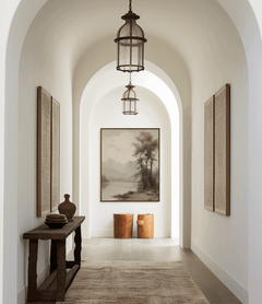 Moody vintage landscape wall art framed at end of arched hallway with rustic decor