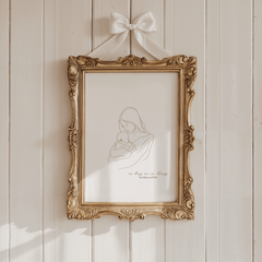Mother and baby line art print in an ornate gold frame hung with a white ribbon bow on a cream panelled wall