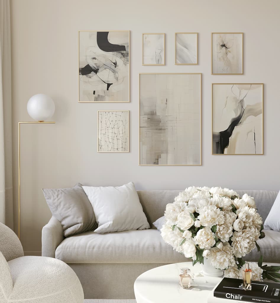 Neutral black and beige abstract gallery wall prints above a table with a white floral centrepiece