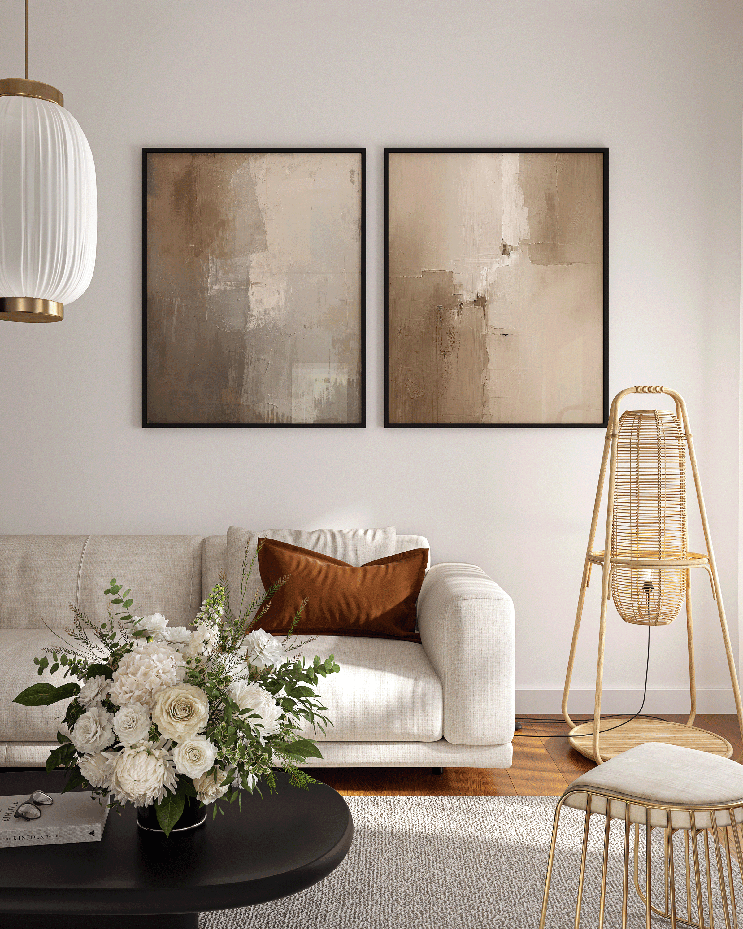 pair of moody beige and brown abstract wall art prints in black frames displayed above a light sofa in a bright living room with floral arrangement and modern décor