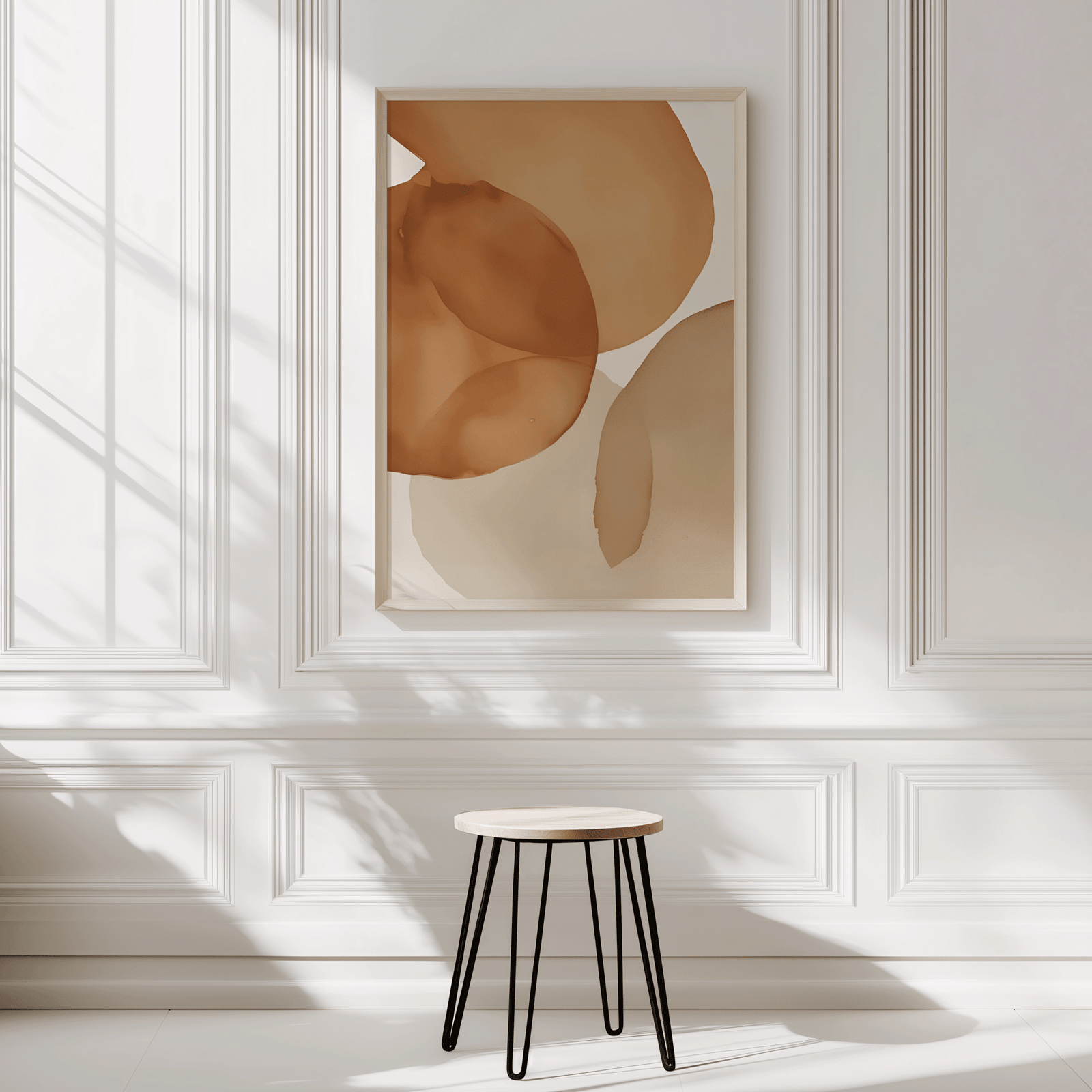 Minimal neutral terracotta watercolor abstract framed art print on white paneled wall with stool. Artwork has a mix of beige, cream, light orange, soft brown iin muted tones.