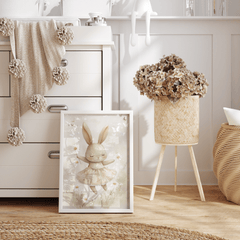 Neutral bunny print in a natural frame leaning beside a white nursery dresser with dried hydrangeas