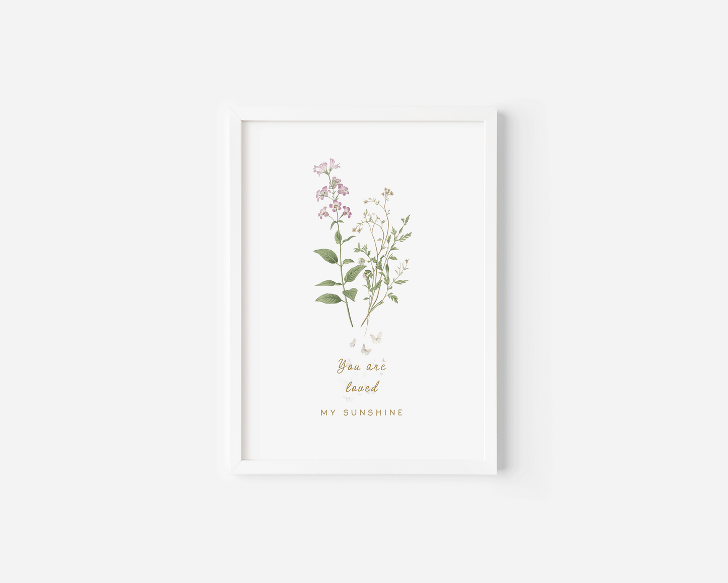 Neutral floral wall art in a white frame featuring soft pastel botanicals, styled in a bright minimalist nursery setting.