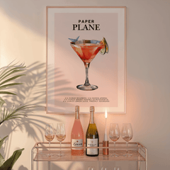 Paper Plane wall art in a natural frame above a glass bar cart with wine bottles and a candle