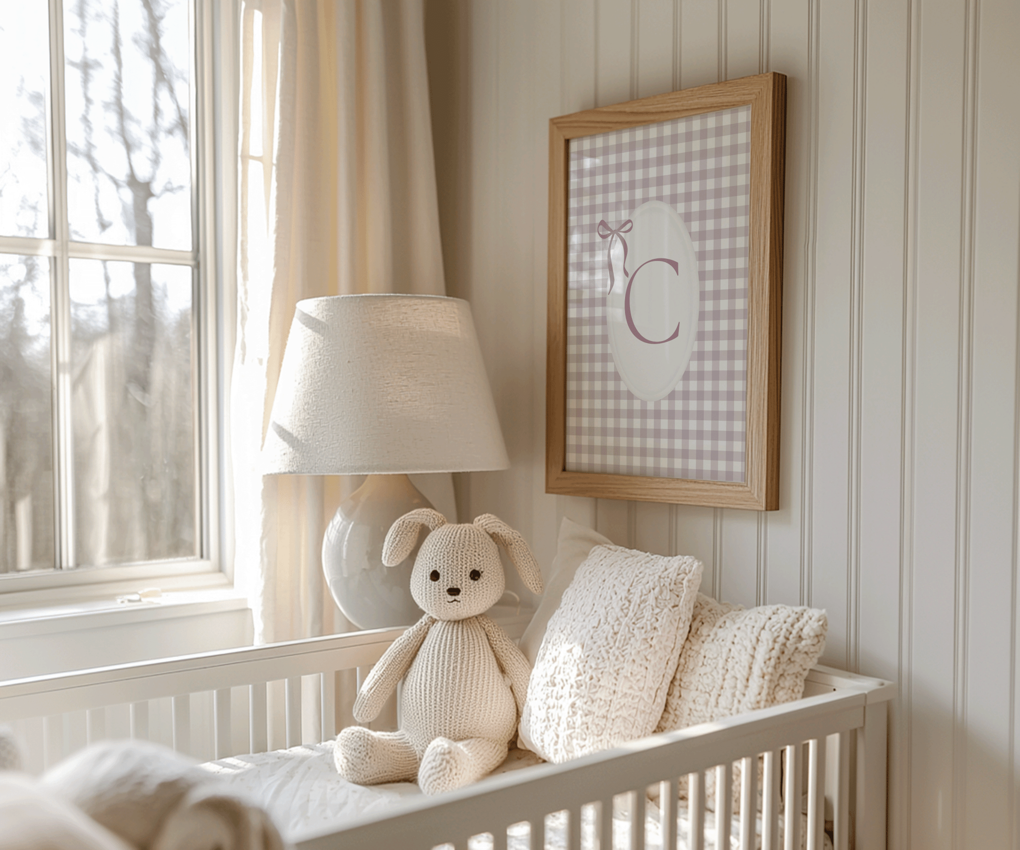 Custom nursery wall art with pink gingham monogram letter C and ribbon bow in wood frame beside lamp and above a neutral crib