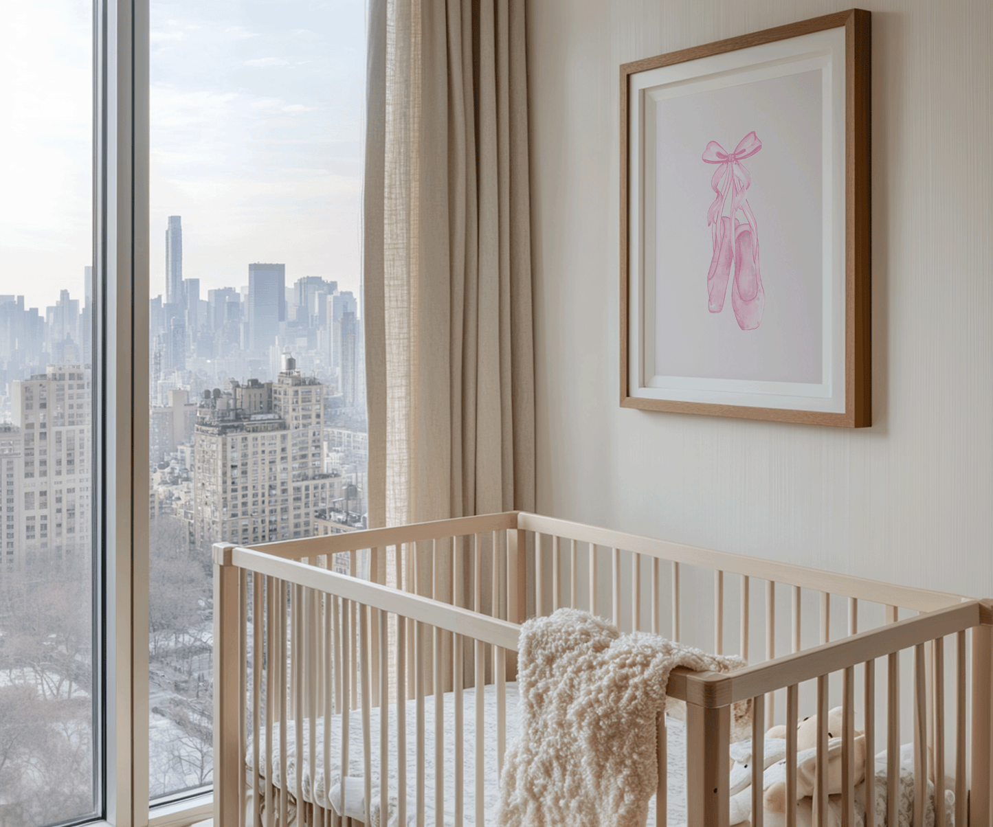 A wood-framed canvas wall art print with pink ballet slippers and pink bow on beige wall above a light wood crib in a modern nursery