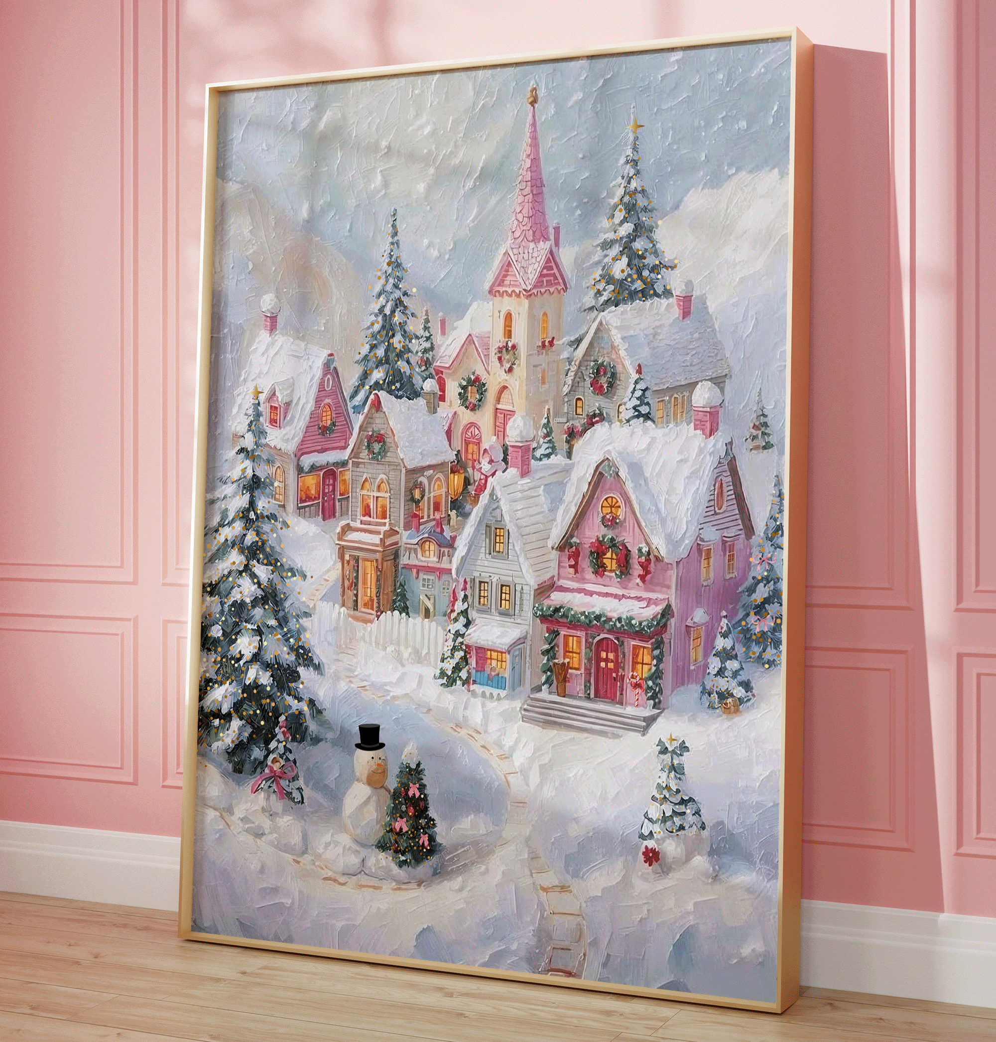 Pink Christmas Village wall art in a gold frame leaning on a blush pink wall, snowy pastel oil painting style canvas print for elegant Christmas or seasonal living room decor, winter landscape scene oil painting texture with whimsical aesthetic