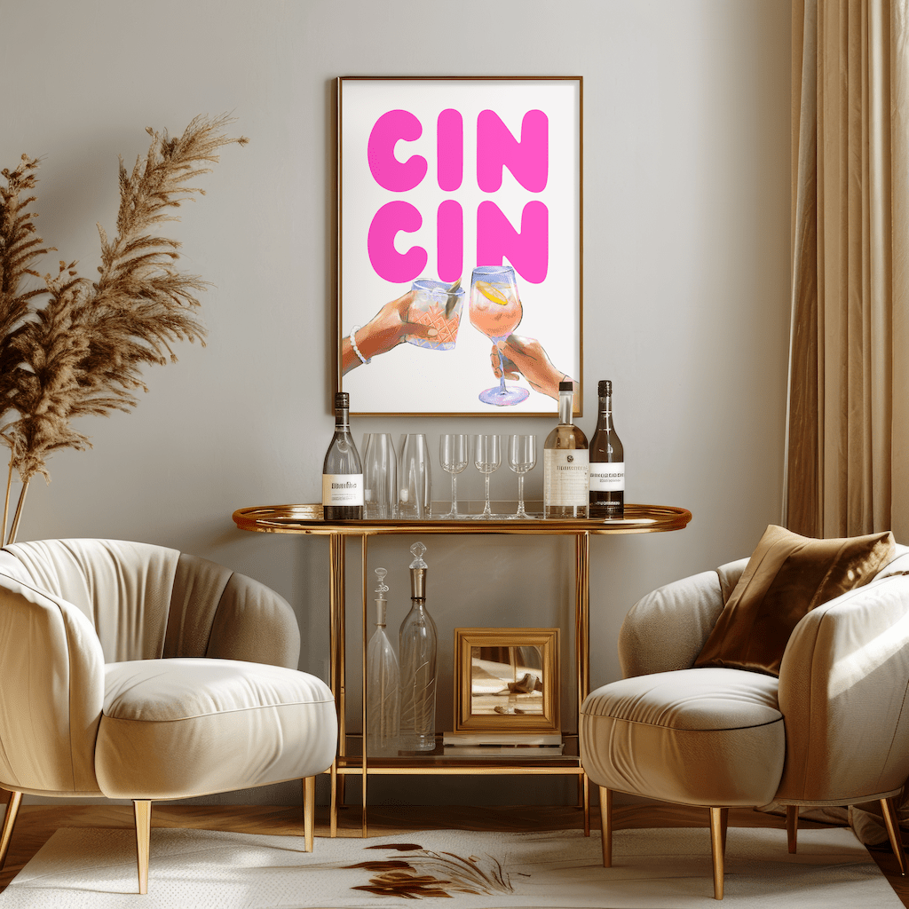 Pink cin cin print in a natural frame above a gold bar cart between two cream armchairs