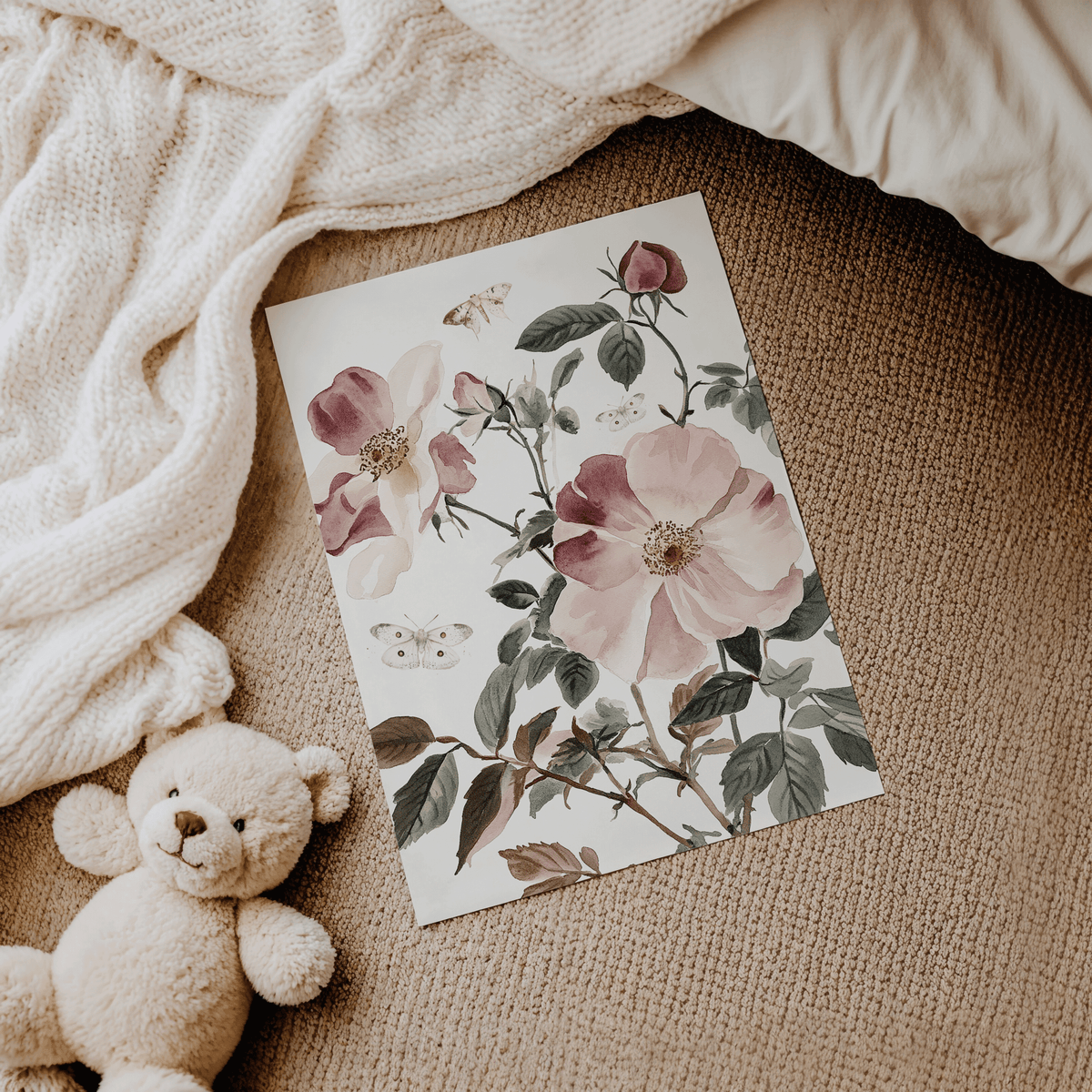 Pink rose nursery print lying on a soft blanket beside a teddy bear