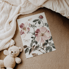 Pink rose nursery print lying on a soft blanket beside a teddy bear