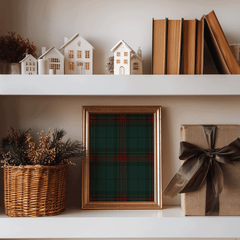 Plaid Christmas wall art in a gold frame on a shelf styled with books and holiday greenery