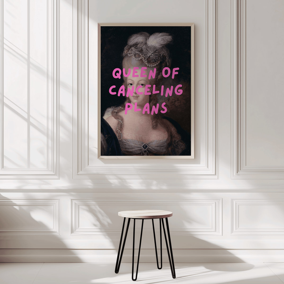 Queen of Canceling Plans print on a white panelled wall above a small stool