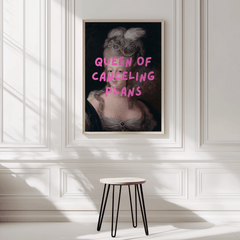 Queen of Canceling Plans print on a white panelled wall above a small stool