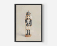Close-up product mockup of a vintage nutcracker Christmas canvas in a black frame against a soft beige background