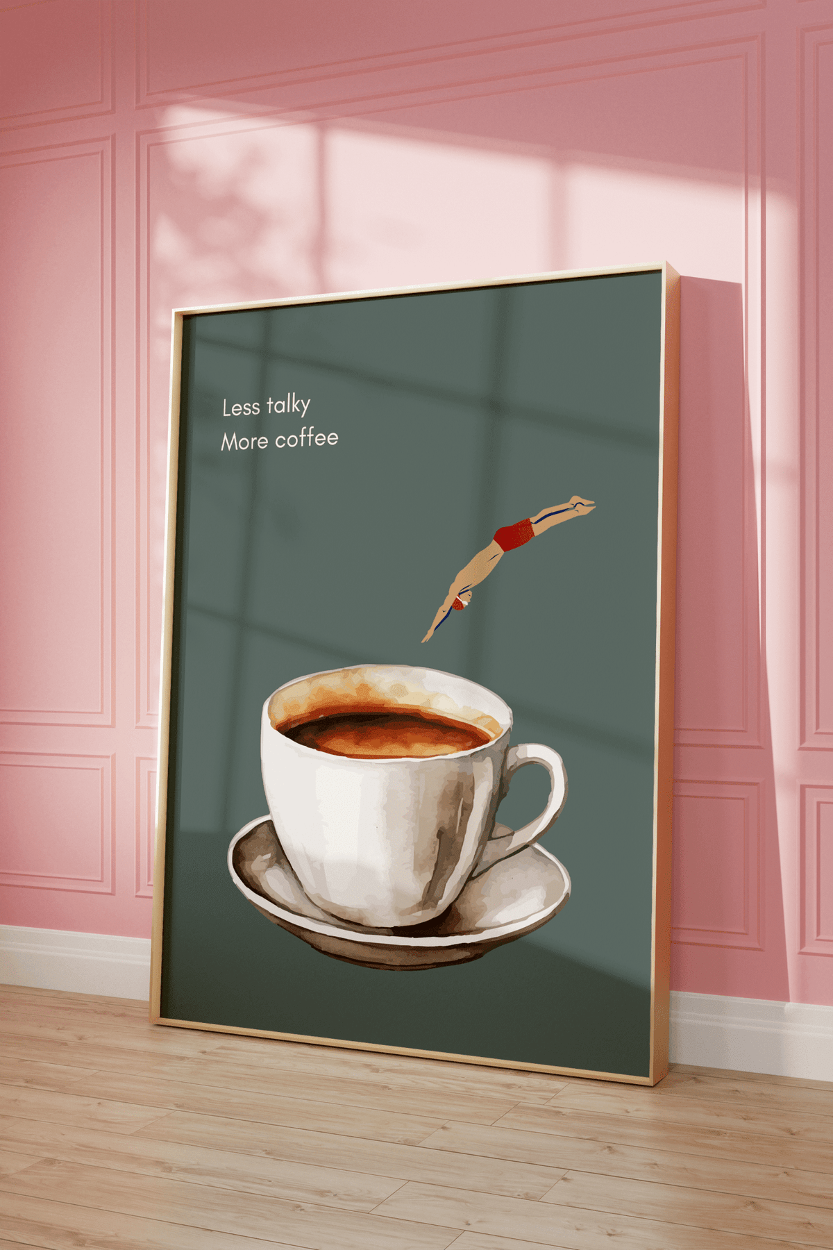 Sage green coffee wall art in a natural wood frame leaning against a pink panelled wall