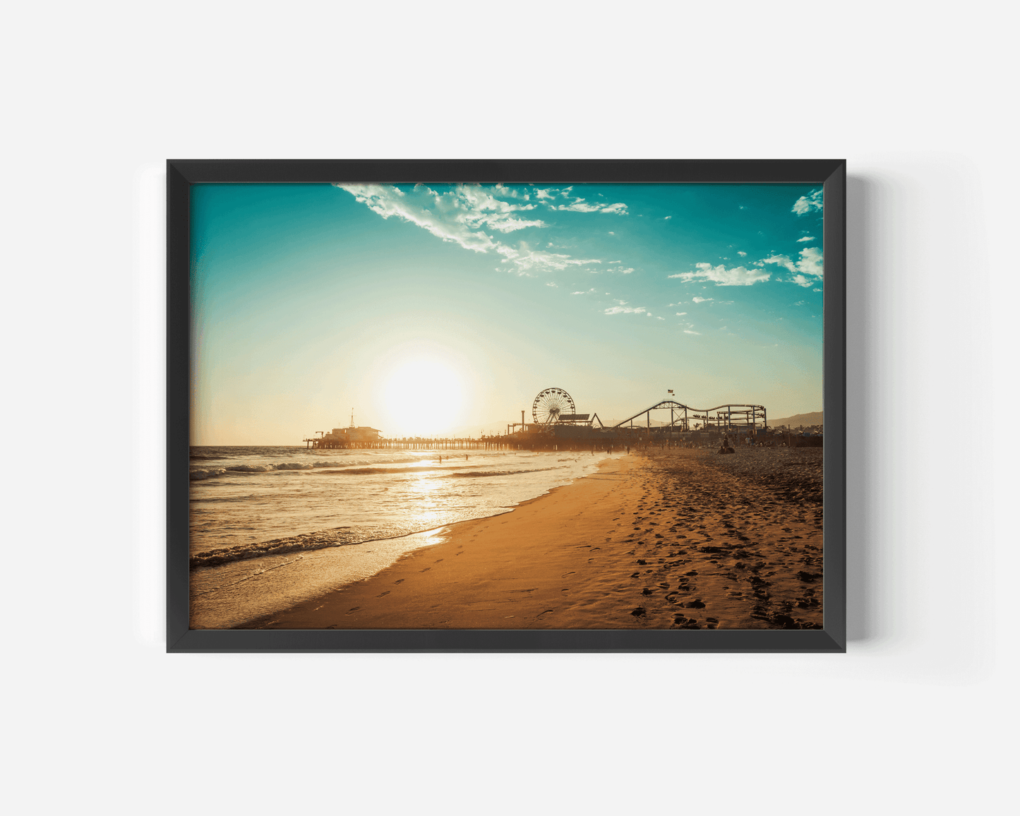 Black framed artwork of Santa Monica Pier beach scene with a pier and sunset.