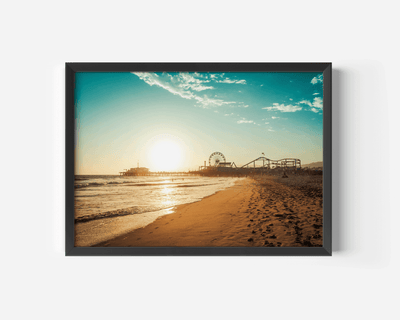 Black framed artwork of Santa Monica Pier beach scene with a pier and sunset.