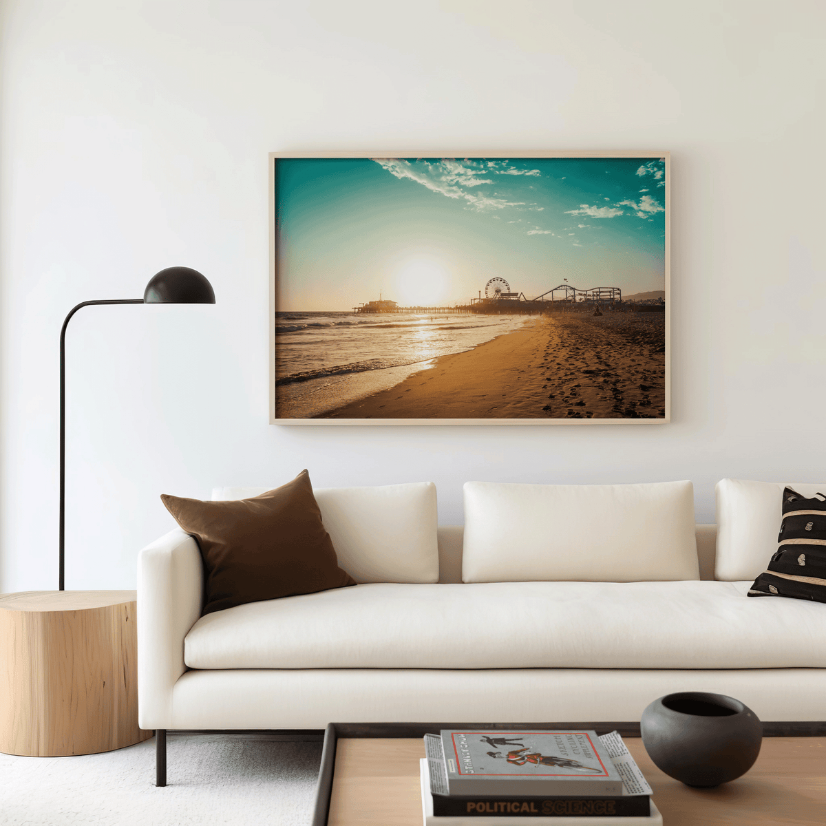 Natural framed Santa Monica canvas wall art print above a white sofa with brown accent pillow