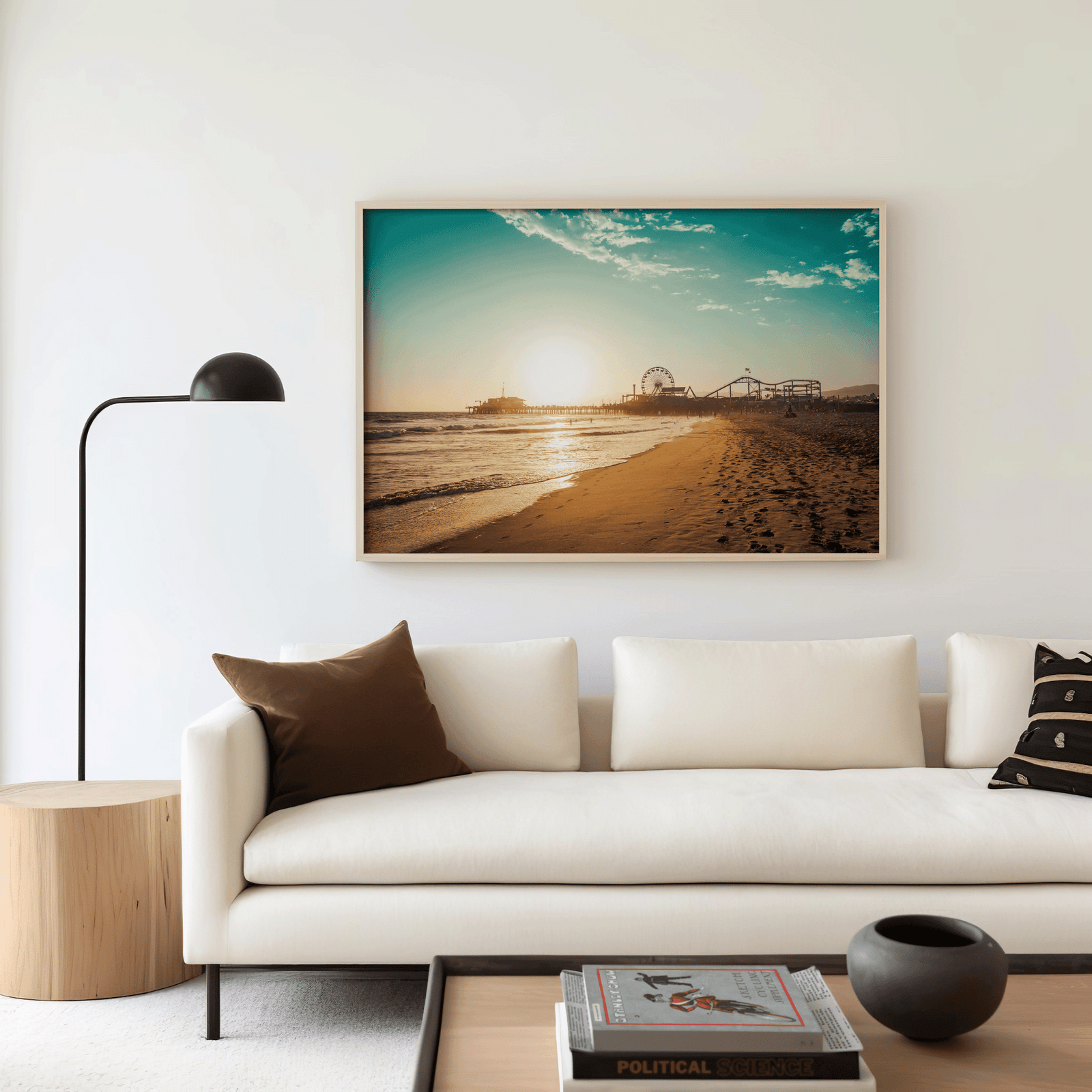 Natural framed Santa Monica canvas wall art print above a white sofa with brown accent pillow