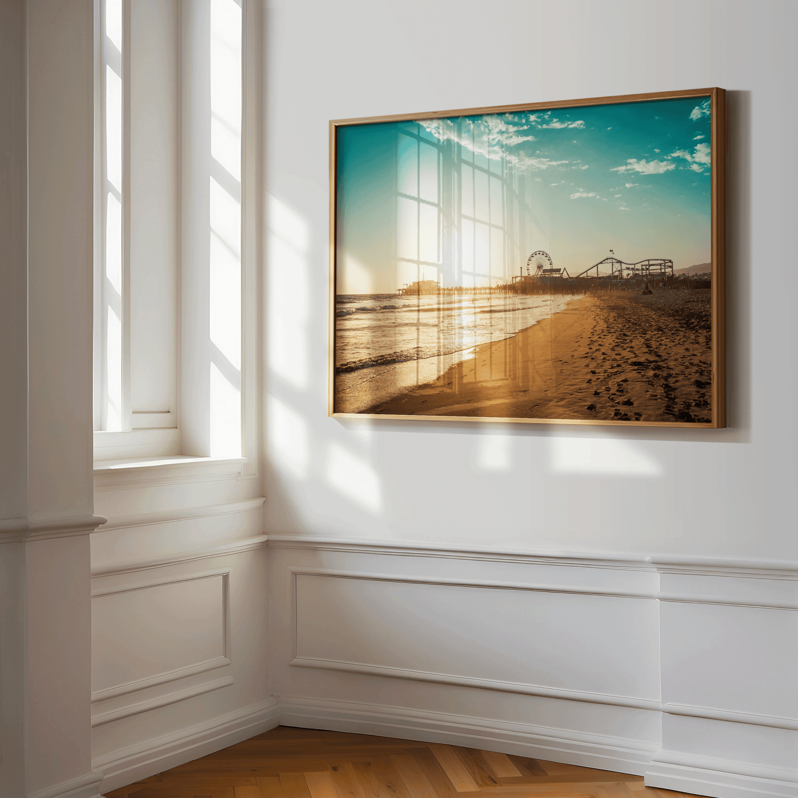 Gold framed Santa Monica Pier wall art print of the pier at sunset, angled in a sunlit white hallway