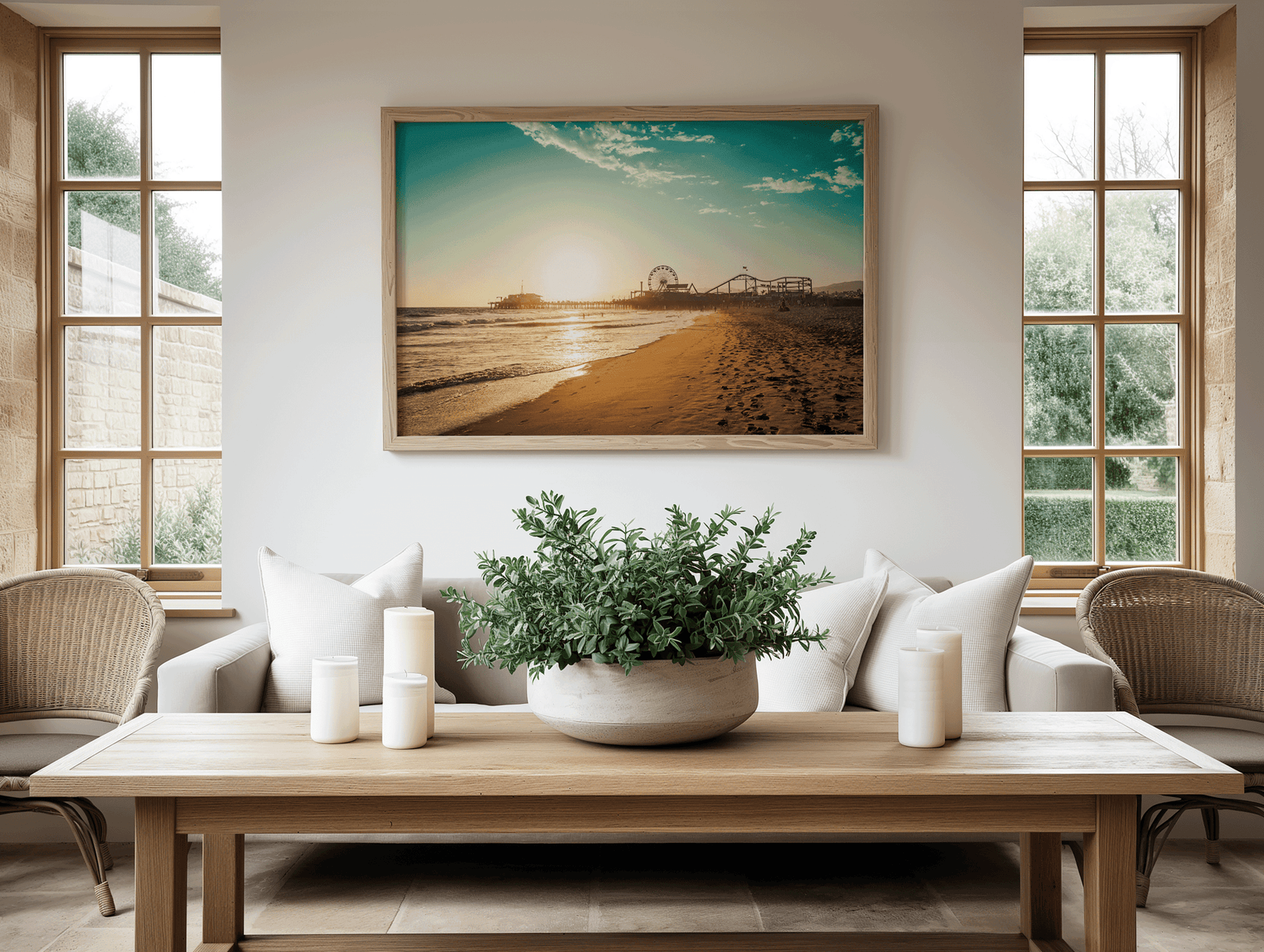 Living room with a Santa Monica Pier beach scene framed wall art above a sofa next to plants, and candles on a wooden table.