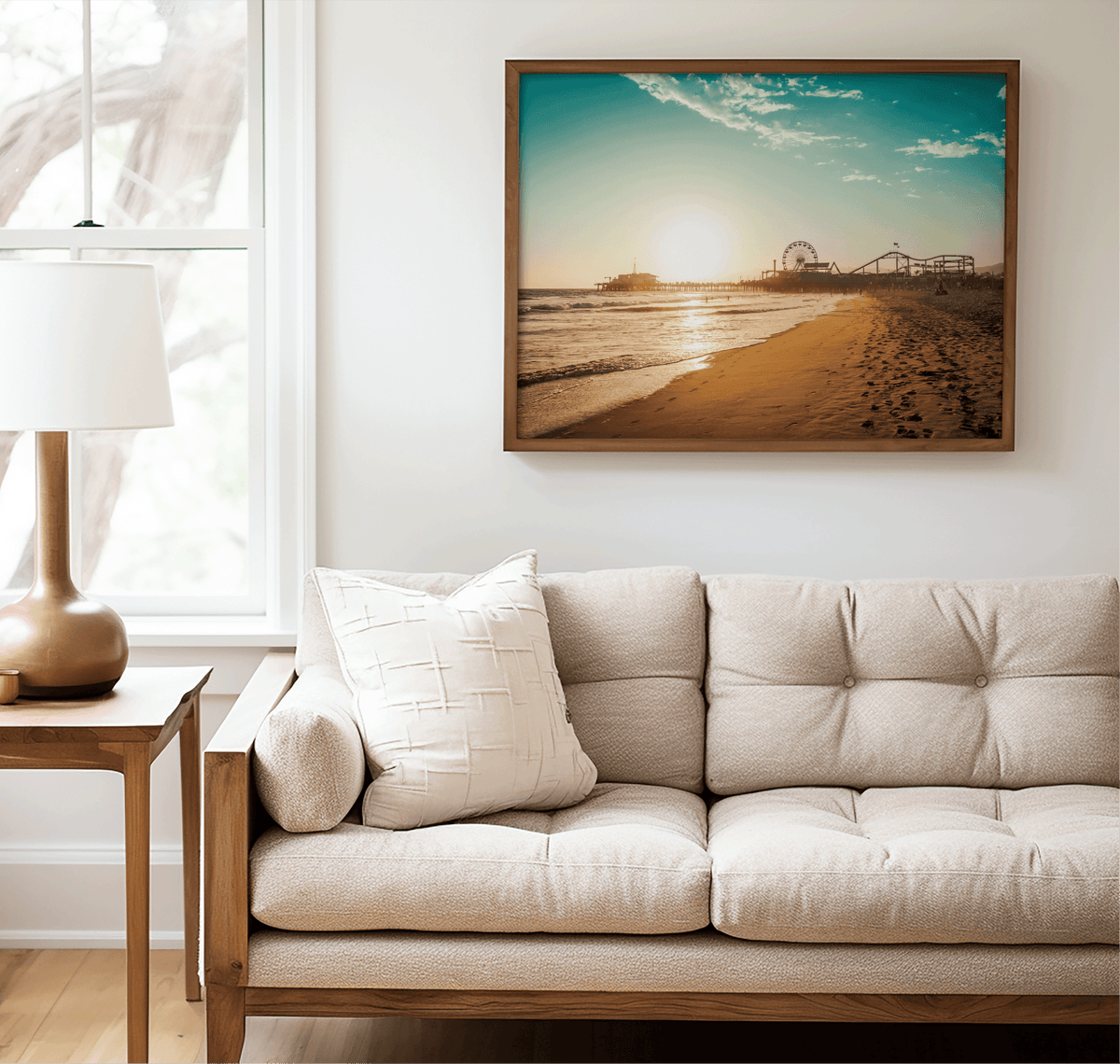 Walnut framed Santa Monica canvas wall art print above a beige sofa beside a lamp and side table