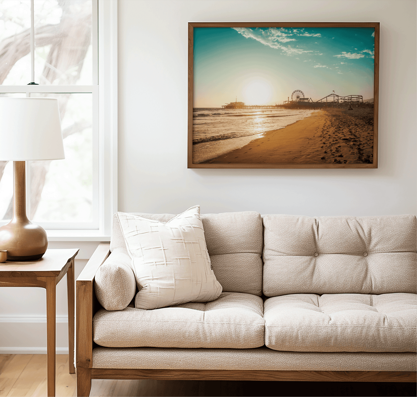 Walnut framed Santa Monica canvas wall art print above a beige sofa beside a lamp and side table