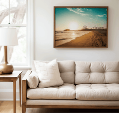 Walnut framed Santa Monica canvas wall art print above a beige sofa beside a lamp and side table