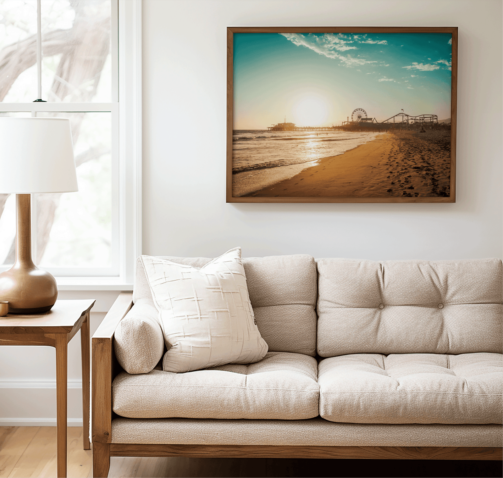Walnut framed Santa Monica canvas wall art print above a beige sofa beside a lamp and side table