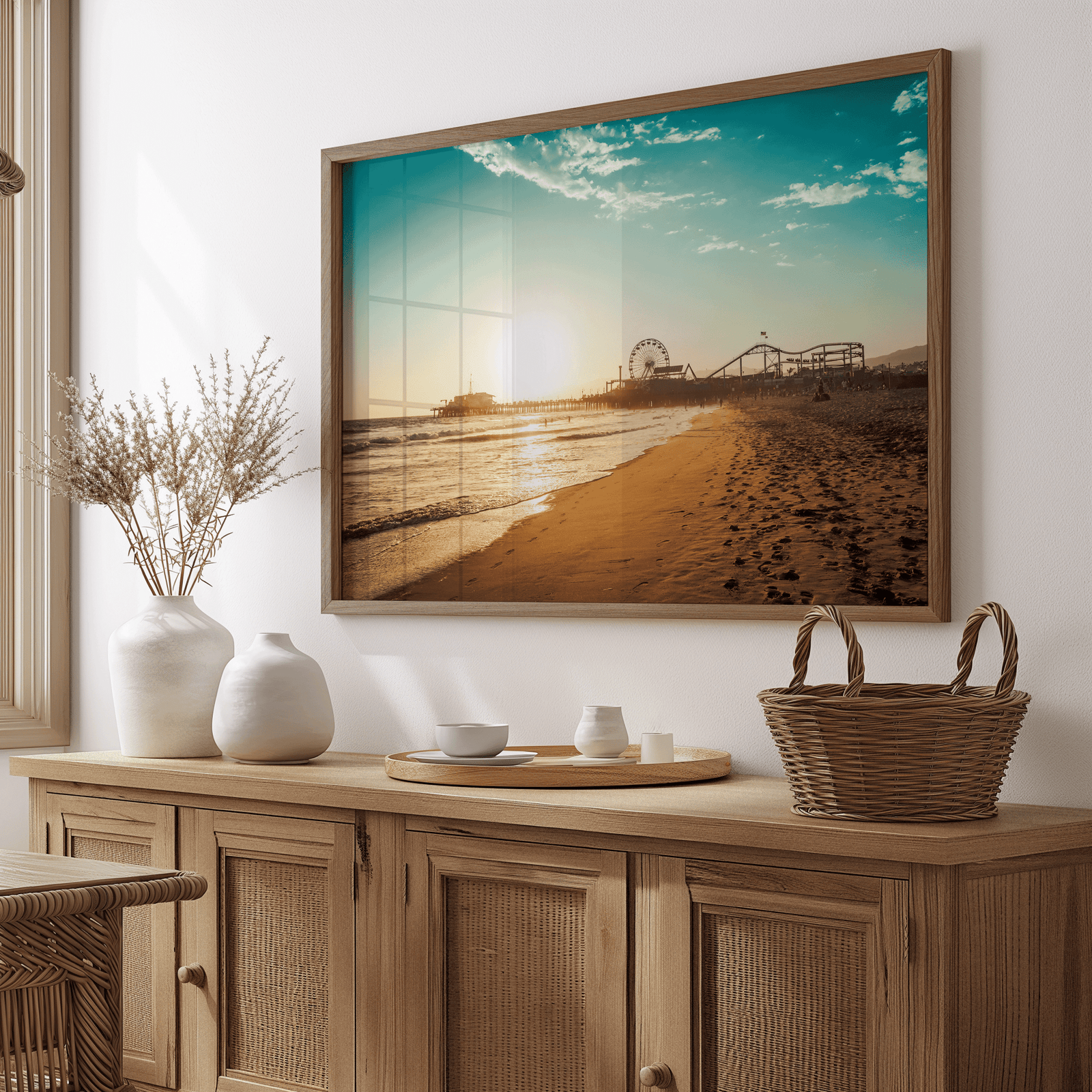 Wood framed Santa Monica wall art above a wooden sideboard with vases and a basket in a dining room