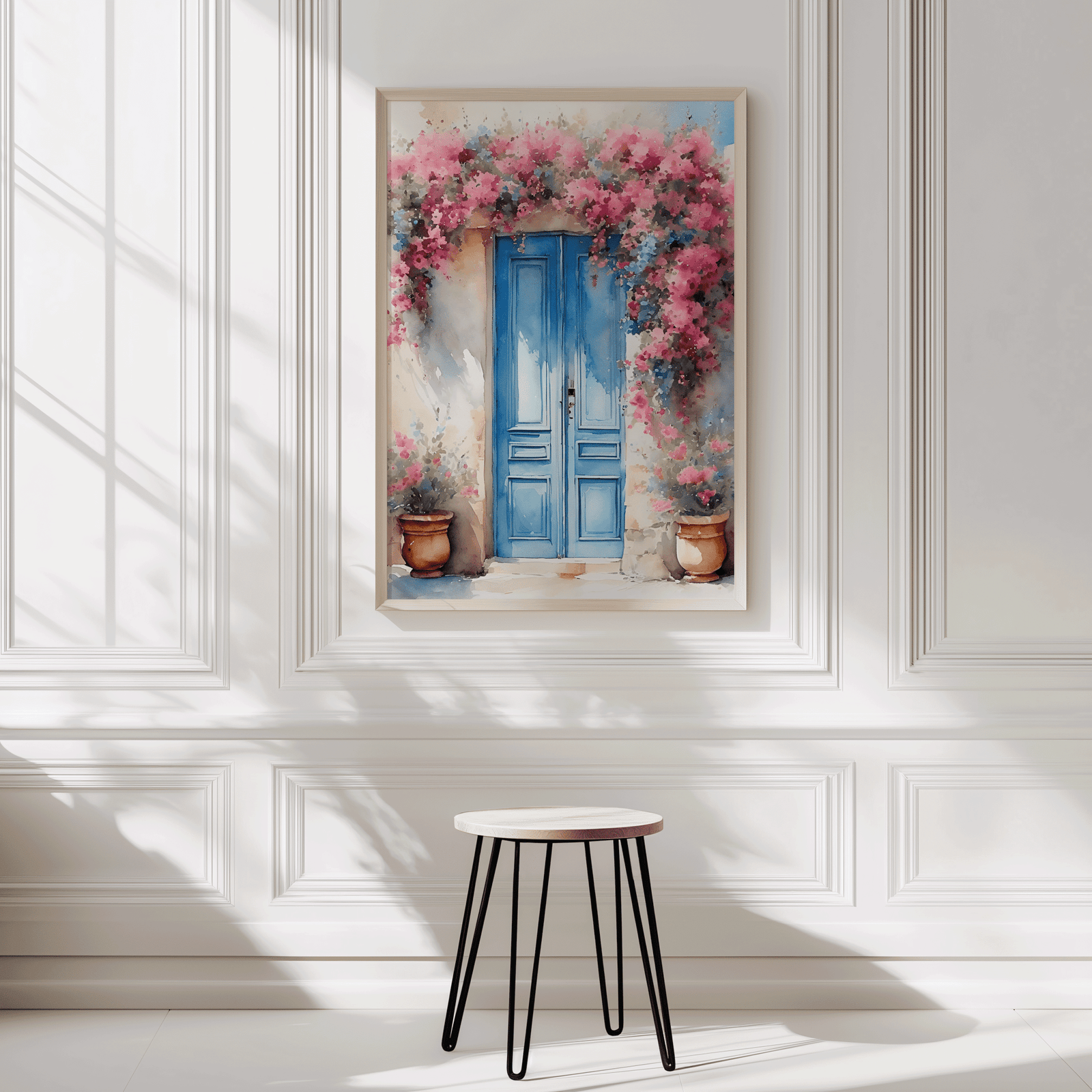 Natural framed Santorini blue door wall art displayed on a white panelled wall beside a stool