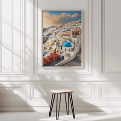 Framed artwork of a Greek village scene in Santorini Greece on a white wall with a stool in front. 