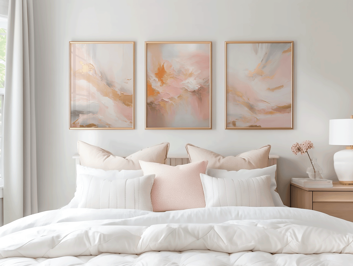 Set of three blush pink and gold abstract wall art prints styled above bed with neutral decor