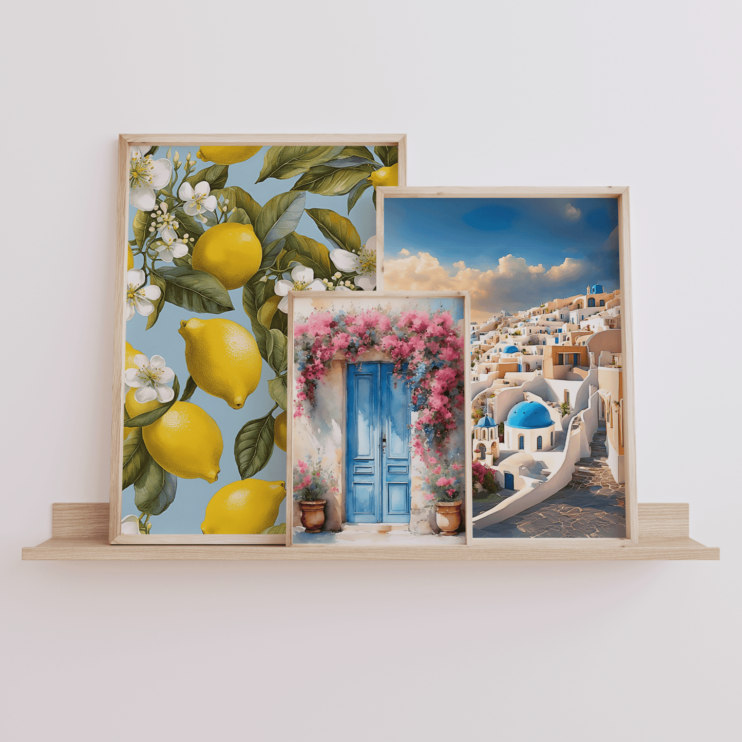 Set of three framed Mediterranean wall art prints on a shelf featuring Santorini, lemons, and a blue Greek door
