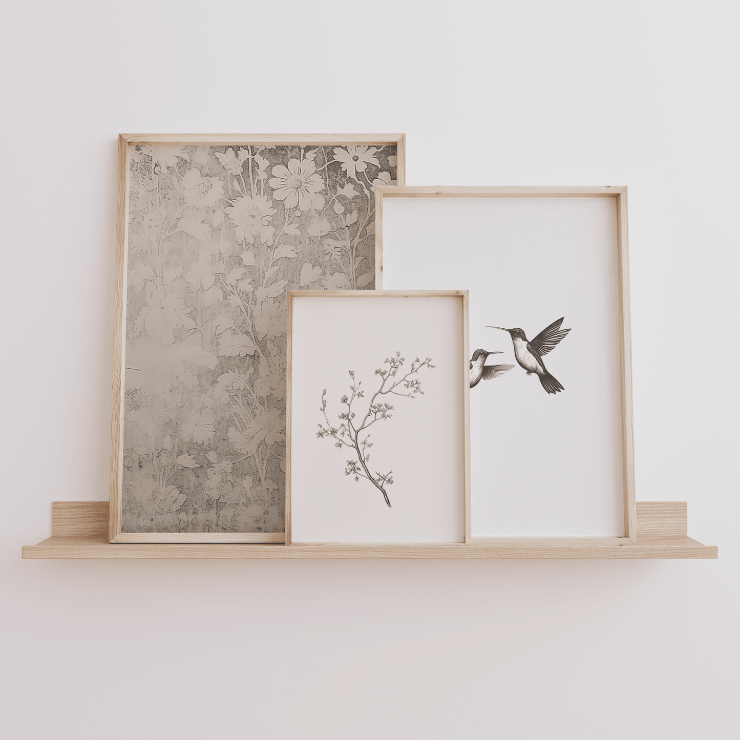Three framed wall art prints with vintage nature aesthetic on a wooden shelf against a white wall