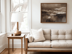 Vintage brown abstract wall art in a wood frame above a neutral sofa in a cozy living room