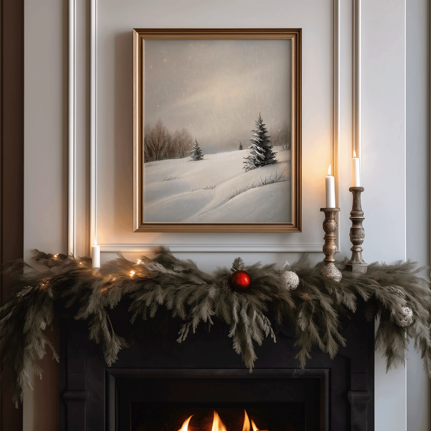 Gold-framed snowy hill landscape hanging above a Christmas mantel decorated with cedar garland, white candles, and soft warm lighting