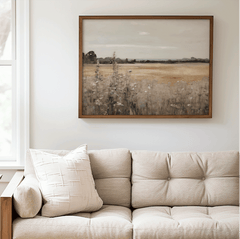 Vintage nature landscape wall art framed above a tufted cream sofa and wooden accents in a bright living room