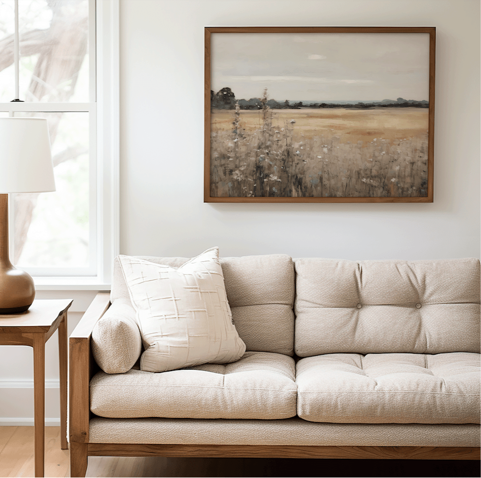 Vintage nature landscape wall art framed above a tufted cream sofa and wooden accents in a bright living room