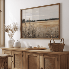 Framed vintage nature landscape wall art above wooden sideboard with wicker basket and ceramic vases